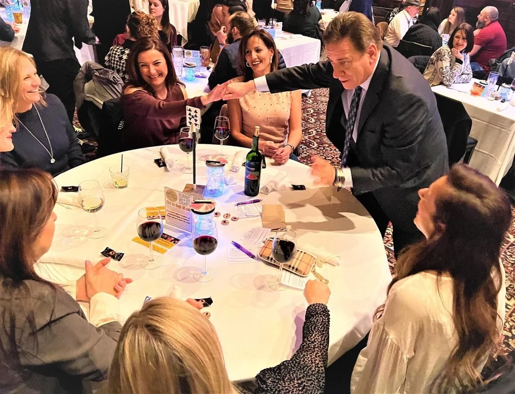 Mike Thornton performing a card trick for guests seated around a banquet table